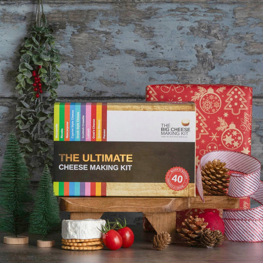 The Ultimate Cheese Making Kit in front of a wrapped Christmas present
