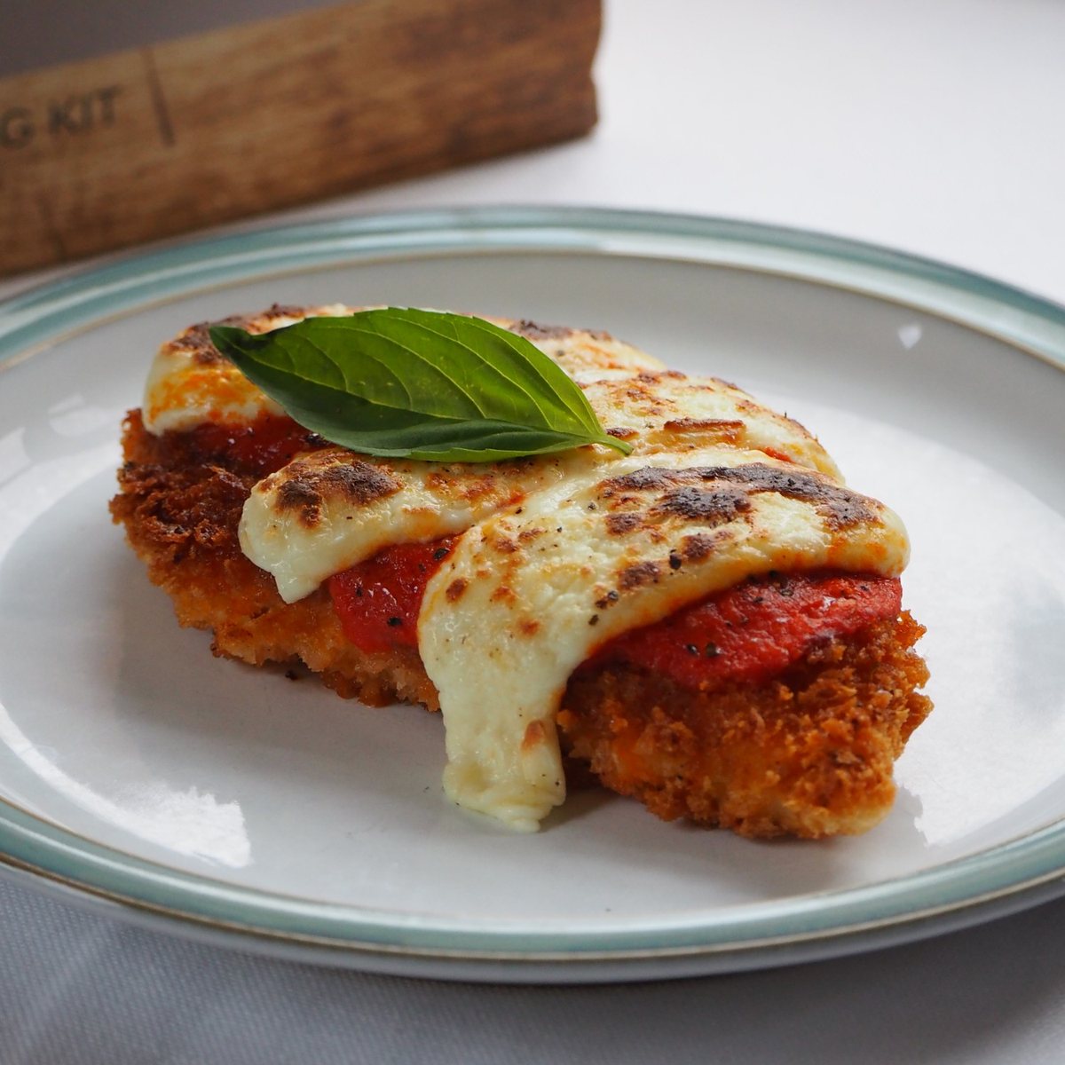 Crispy parmigiana topped with grilled homemade mozzarella, tomato sauce and basil