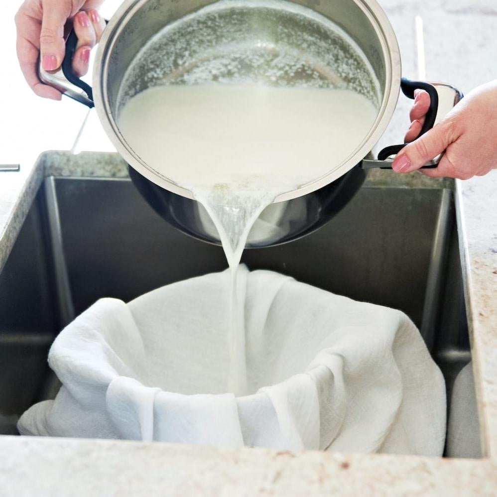 Big Cheese Making Kit: Pouring curds into cheesecloth-lined colander in sink to make goat cheese.
