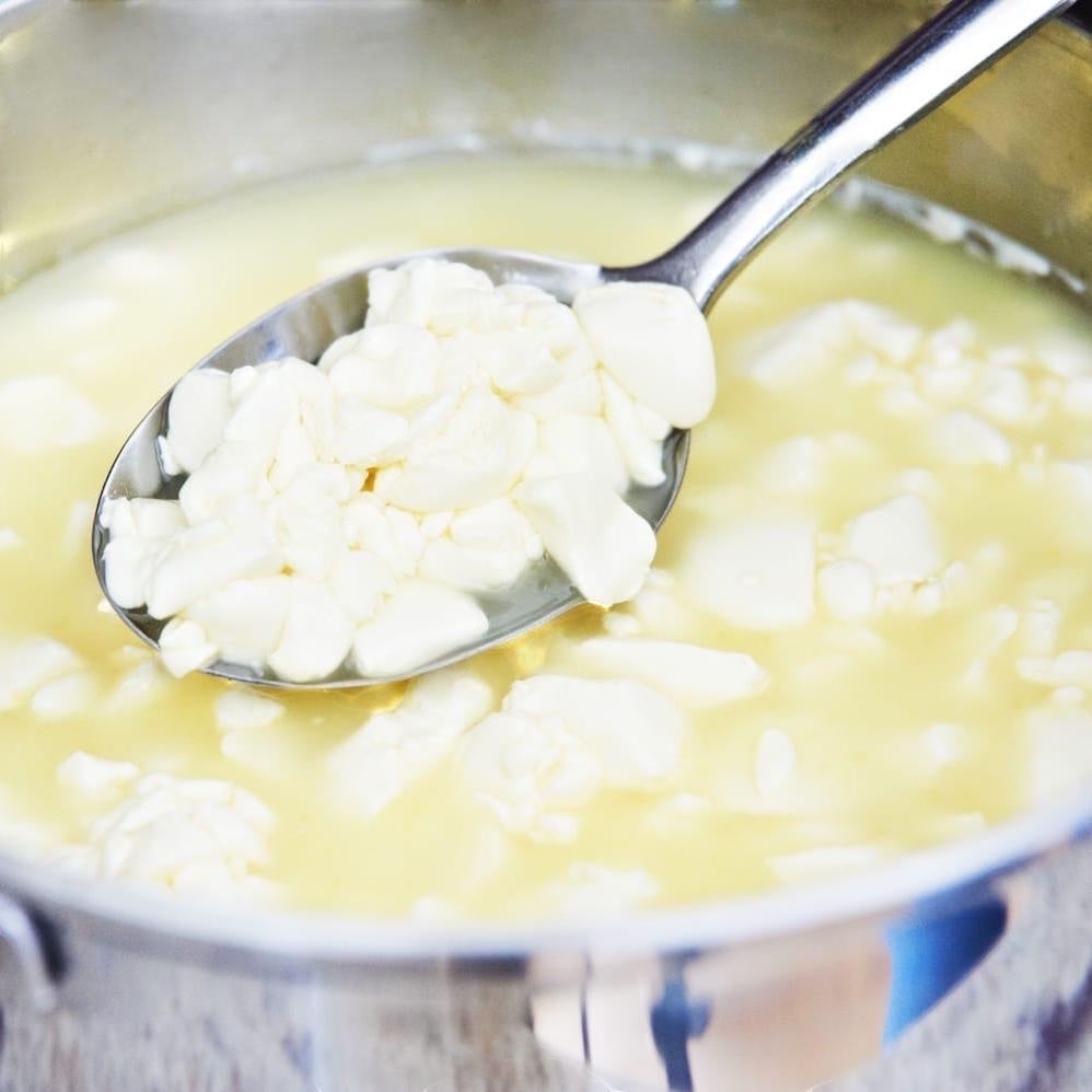 The Big Cheese Making Kit Mediterranean Cheese Making Kit showing fresh curds being scooped from a pot.
