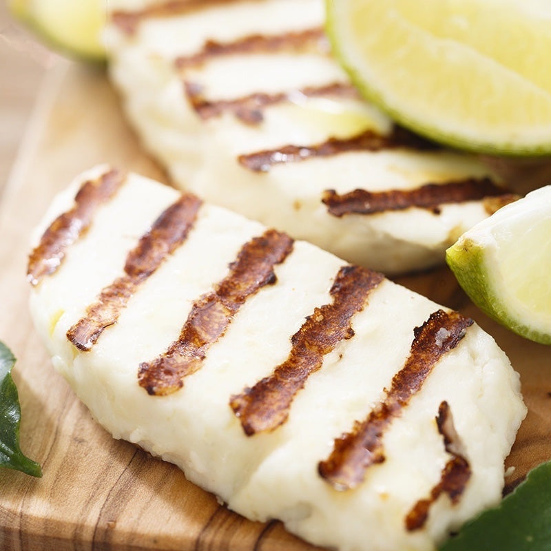Big Cheese Making Kit Wallace & Gromit Squeaky Moon Cheese Making Kit, grilled halloumi cheese with lime wedges on a wooden board.