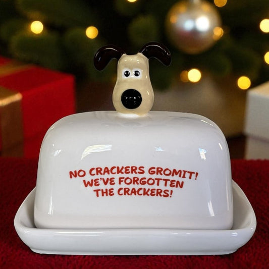 Butter dish with dog design and humorous text in front of a Christmas tree.